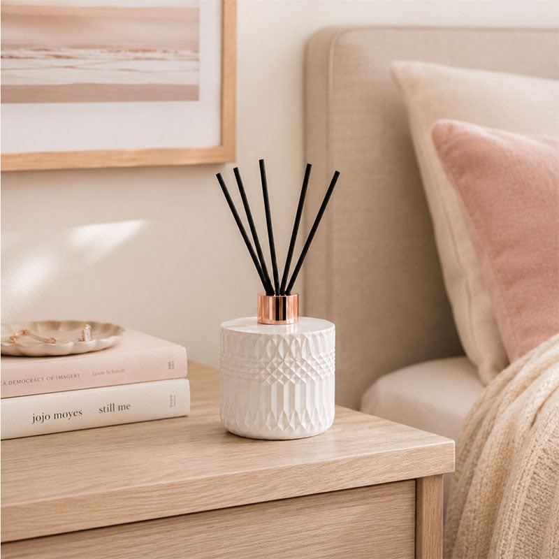 Luxury apartment bedroom styled with a reed diffuser and scented candle for a relaxing atmosphere.