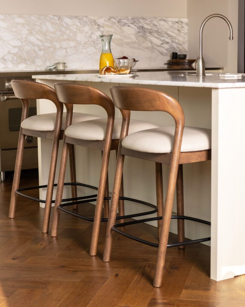 Luxury kitchen with premium upholstered counter stools and minimalist styling.
