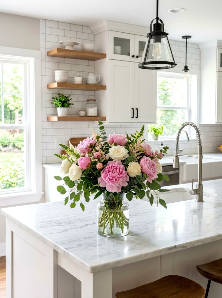 Elegant kitchen featuring fresh flowers in a ceramic vase on a bright countertop.
