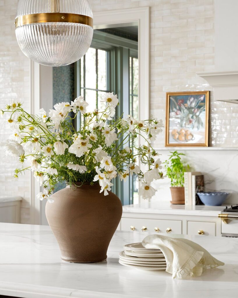 Modern kitchen featuring a large sculptural ceramic vase with fresh greenery.